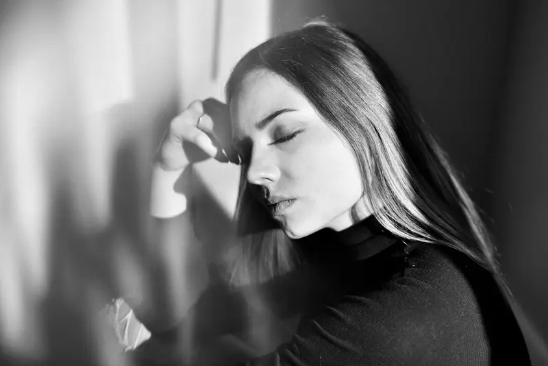 Vrouw in een zwarte trui tegen een donkere achtergrond